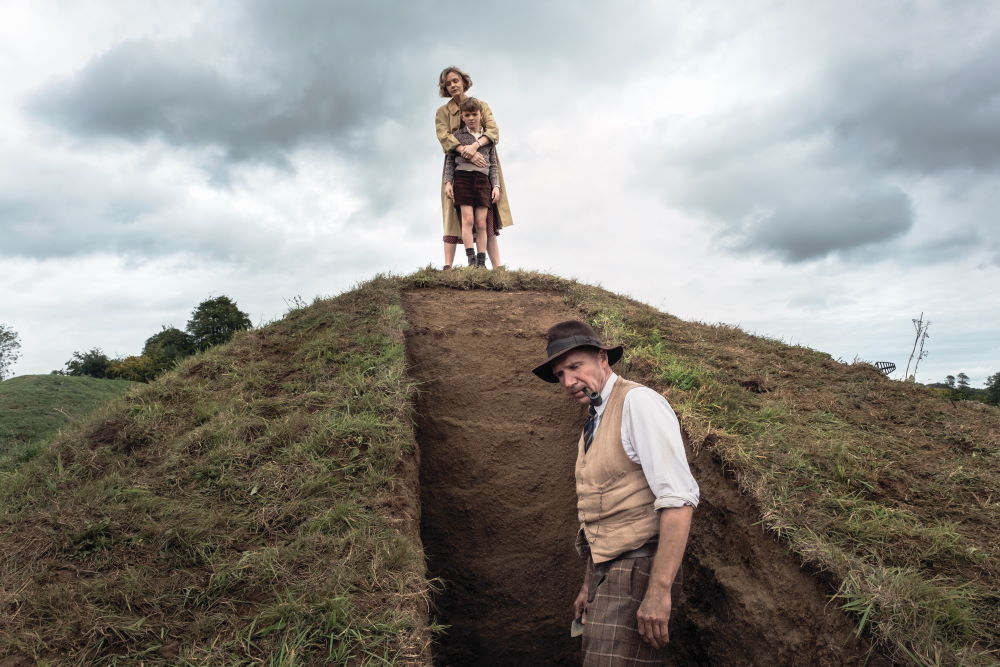 Ralph Fiennes as Basil Brown, Carey Mulligan as Edith Pretty, and Archie Barnes as her son Robert, at the recreated Sutton Hoo mound in The Dig.